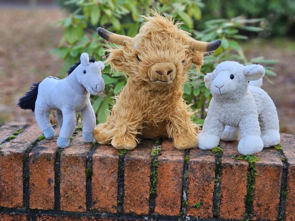 Esel-, Ochse- und Schafkuscheltiere auf einer Mauer