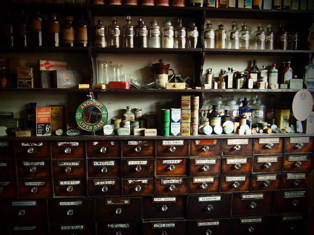 Das Regal einer alten Apotheke mit vielen Gläsern und Schachteln.